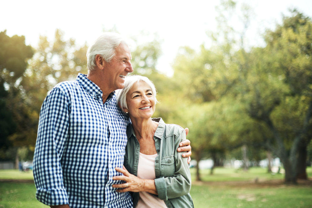 elderly couple in a park smiling